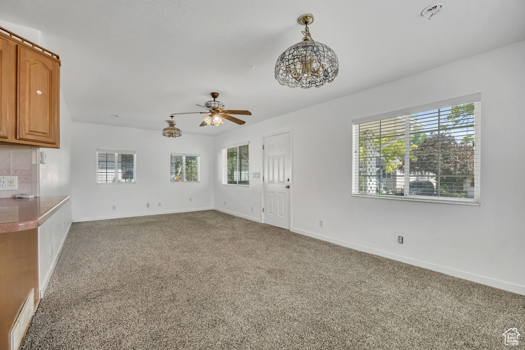 Unfurnished living room featuring plenty of natural light, carpet, and ceiling fan