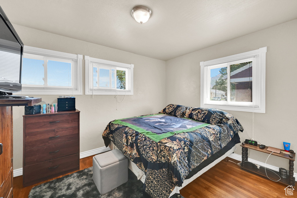 Bedroom with multiple windows, baseboards, and wood finished floors