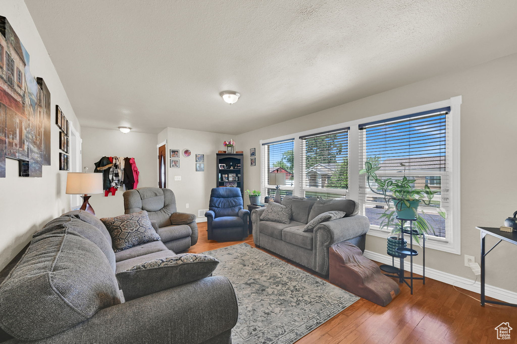 Living area featuring baseboards, wood finished floors, and a textured ceiling