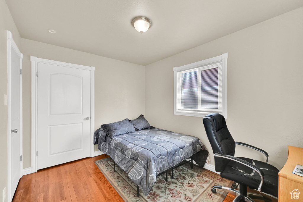 Bedroom with wood finished floors, an office area, and baseboards