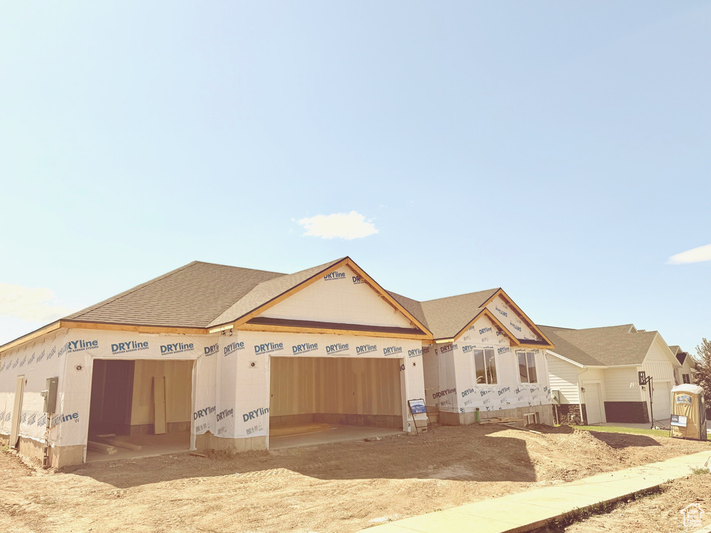 Unfinished property featuring a garage and a shingled roof