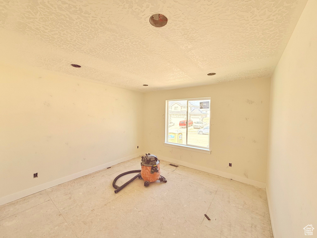 Empty room featuring a textured ceiling and baseboards
