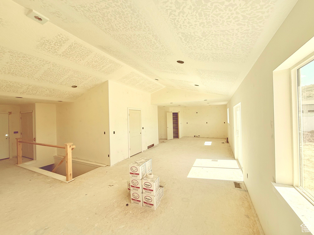 Unfurnished room with plenty of natural light, lofted ceiling, and a textured ceiling