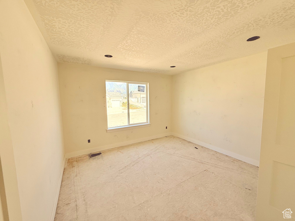 Empty room with a textured ceiling and baseboards