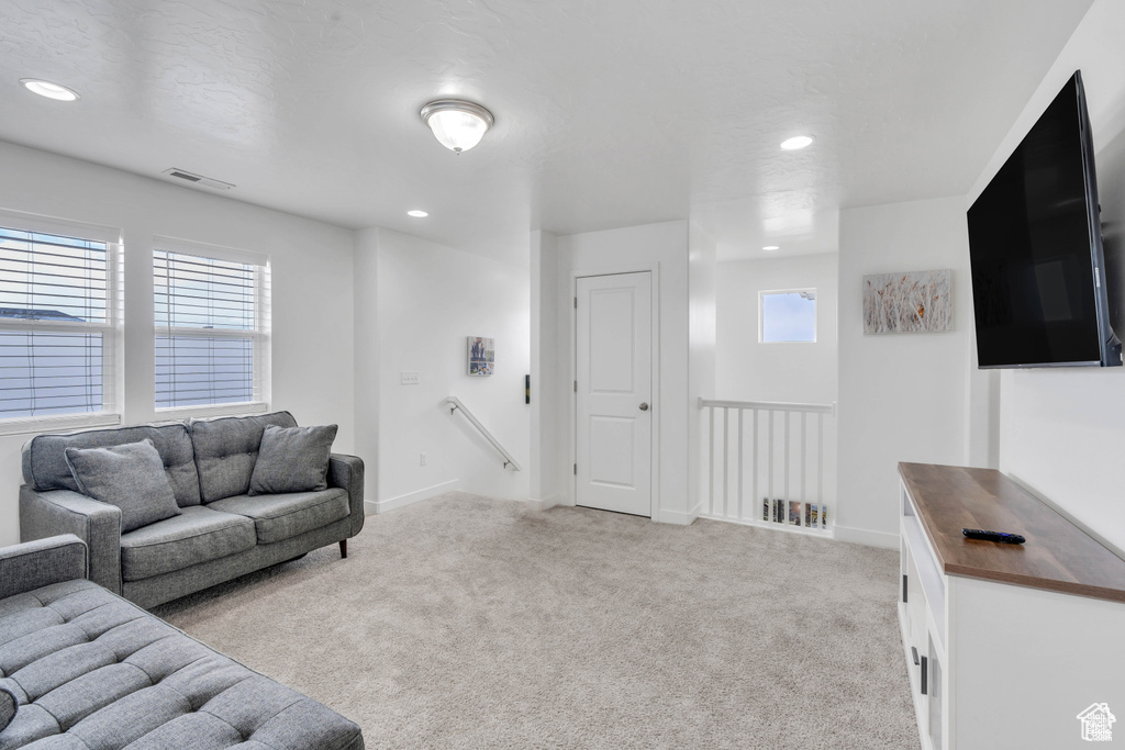 Living area featuring healthy amount of natural light, light carpet, recessed lighting, and baseboards
