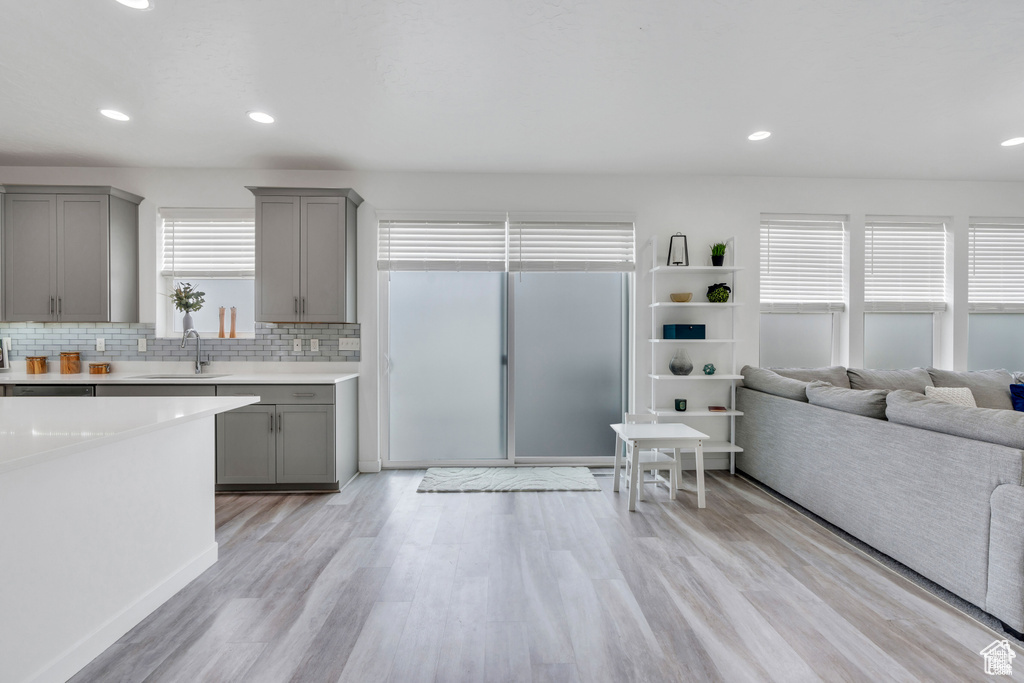 Kitchen featuring gray cabinetry, a sink, light wood-type flooring, light countertops, and decorative backsplash