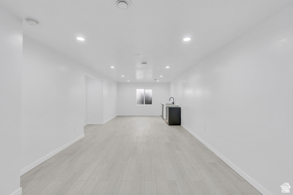 Unfurnished living room featuring recessed lighting, baseboards, light wood-style floors, and a sink
