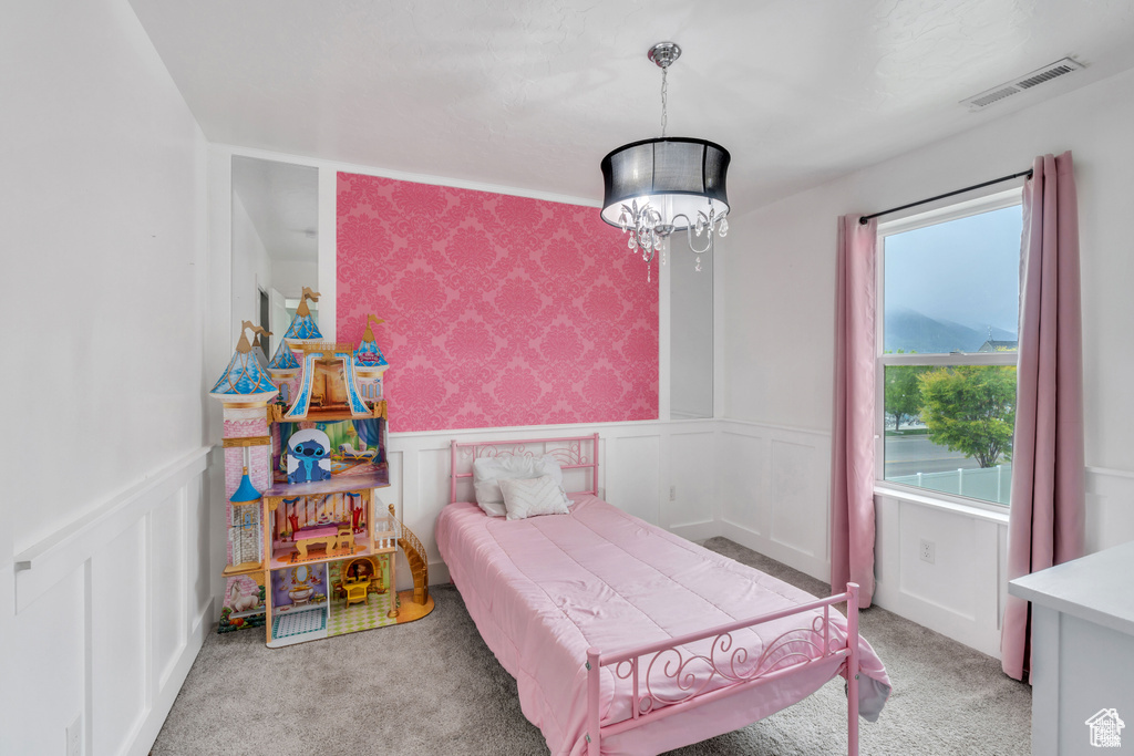 Bedroom featuring carpet flooring, a wainscoted wall, a chandelier, and a decorative wall