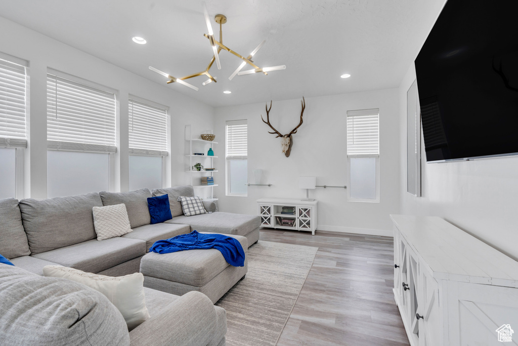 Living area featuring a chandelier, plenty of natural light, light wood-style floors, recessed lighting, and baseboards