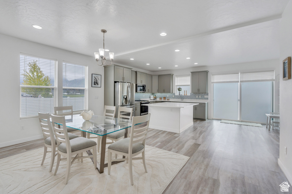 Dining room with healthy amount of natural light, a chandelier, light wood-type flooring, baseboards, and recessed lighting