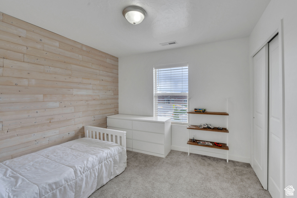 Bedroom featuring wooden walls and light colored carpet