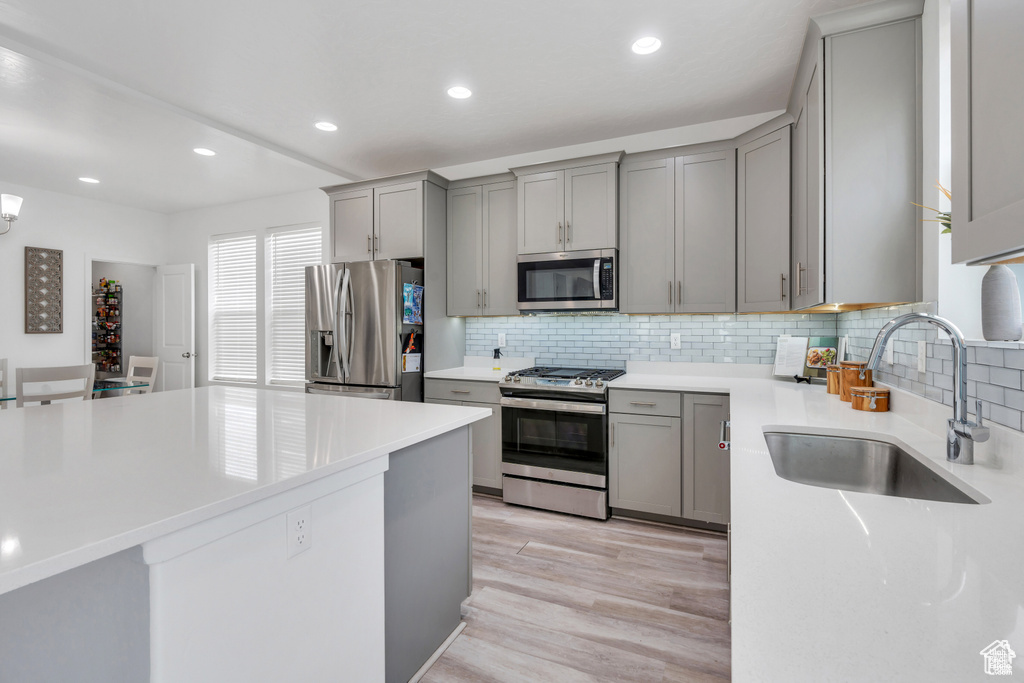 Kitchen with appliances with stainless steel finishes, a sink, gray cabinets, decorative backsplash, and recessed lighting
