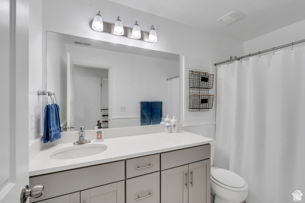 Full bathroom with vanity, toilet, and a shower with shower curtain