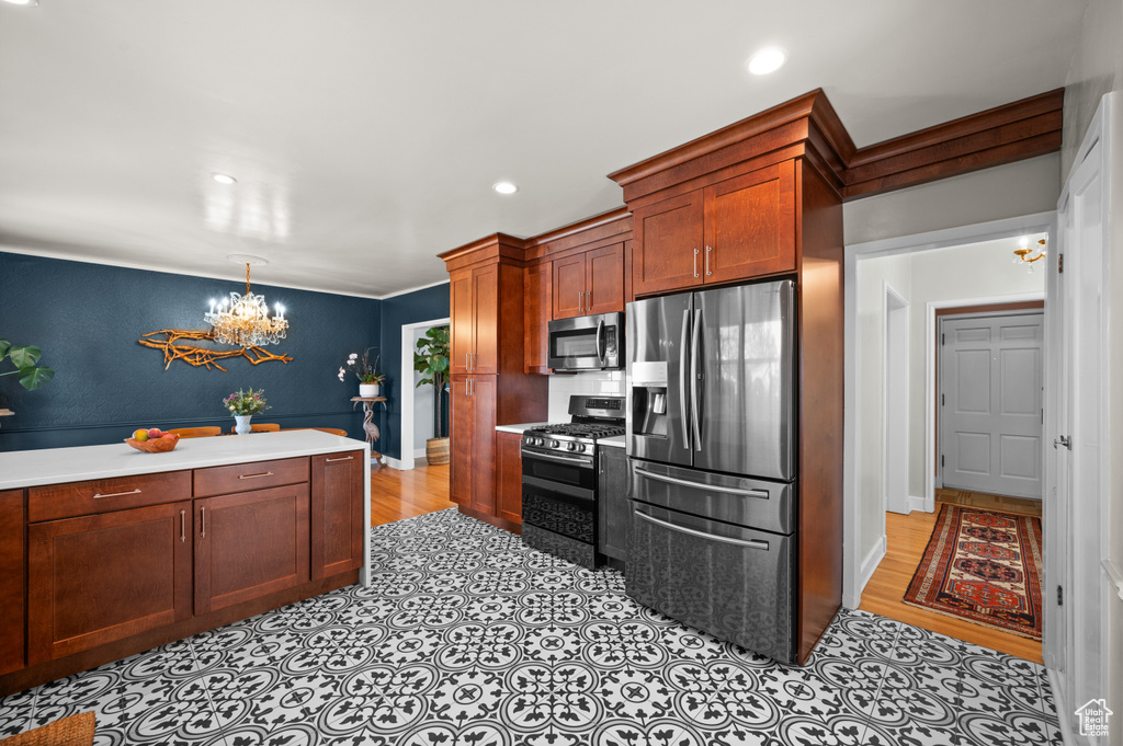 Kitchen with stainless steel appliances, a chandelier, light countertops, baseboards, and recessed lighting