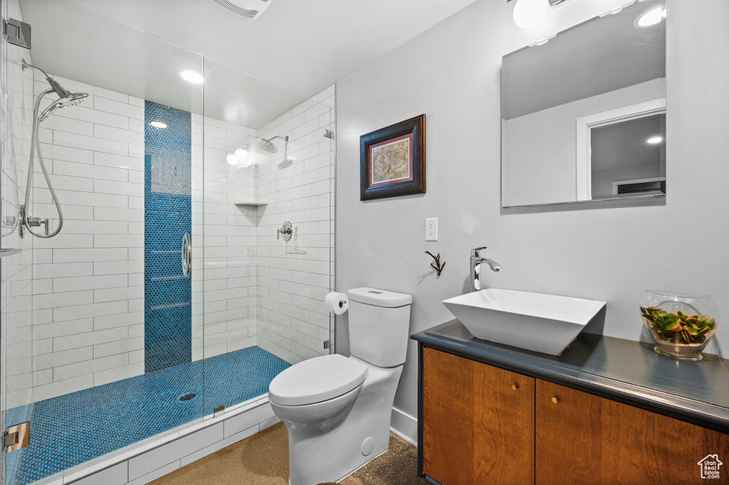 Bathroom featuring toilet, a shower stall, and vanity