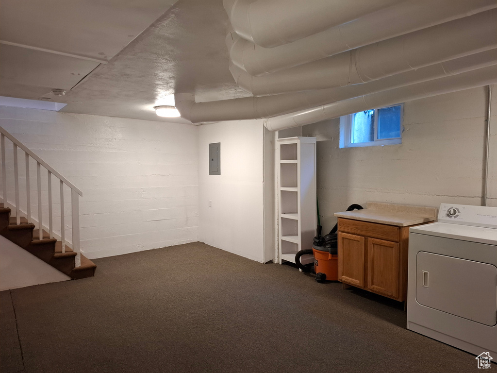 Basement with washer / clothes dryer, electric panel, dark colored carpet, stairs, and concrete block wall