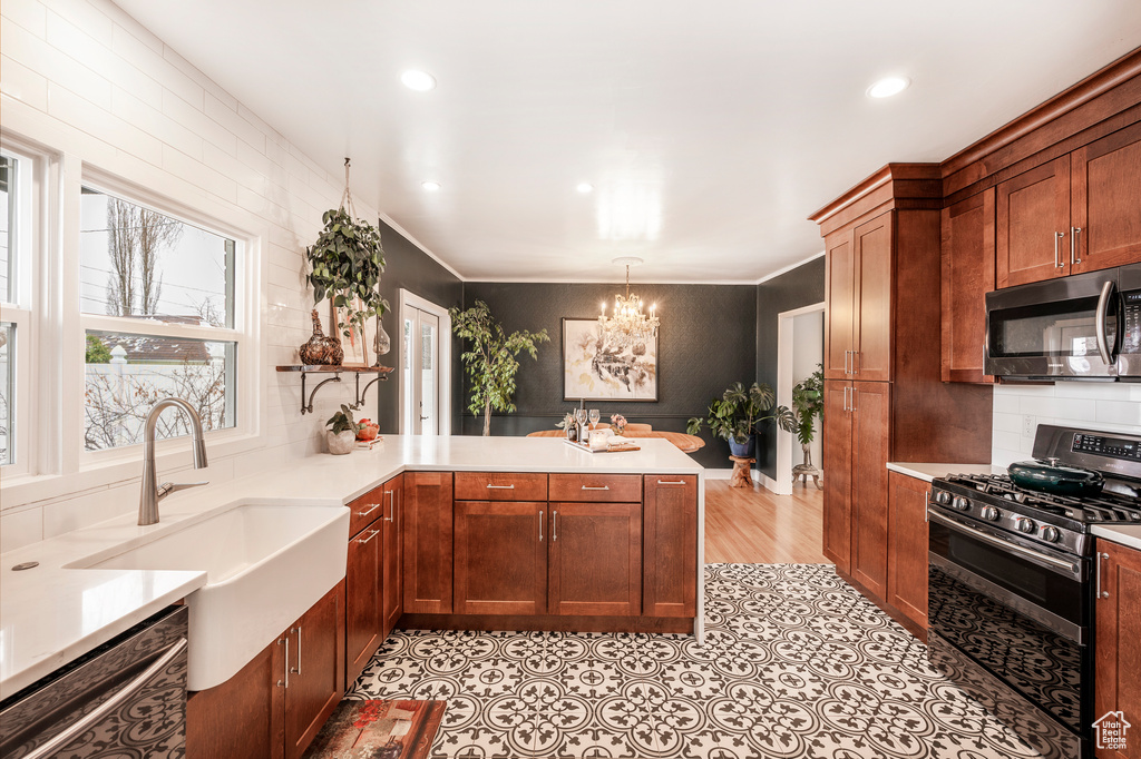 Kitchen featuring stainless steel appliances, a sink, a chandelier, a peninsula, and light countertops