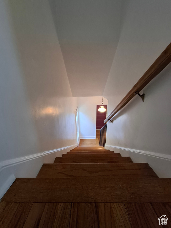 Stairs featuring wood finished floors and vaulted ceiling
