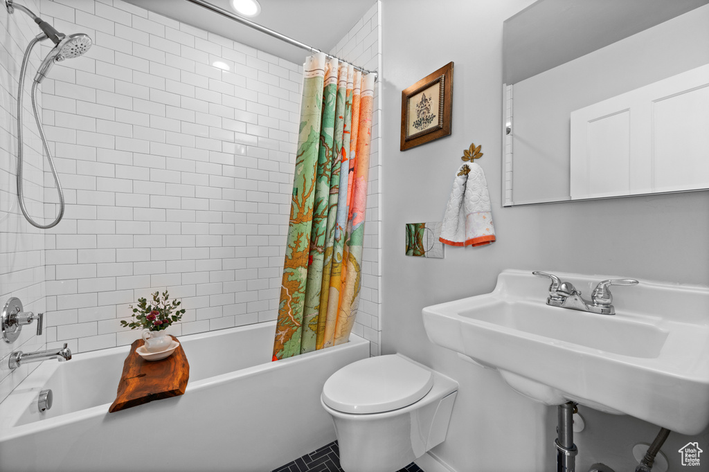 Full bath with shower / bath combo with shower curtain, toilet, and a sink
