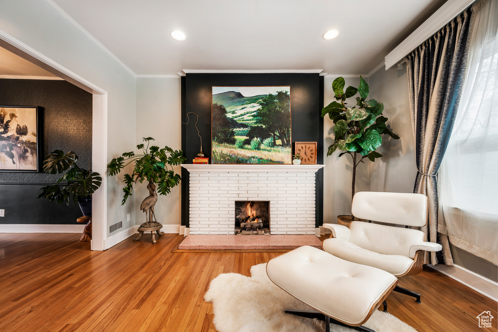 Living area with crown molding, wood finished floors, a fireplace, baseboards, and recessed lighting