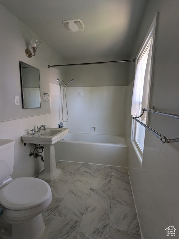 Full bathroom featuring toilet, shower / washtub combination, healthy amount of natural light, and marble look tile flooring