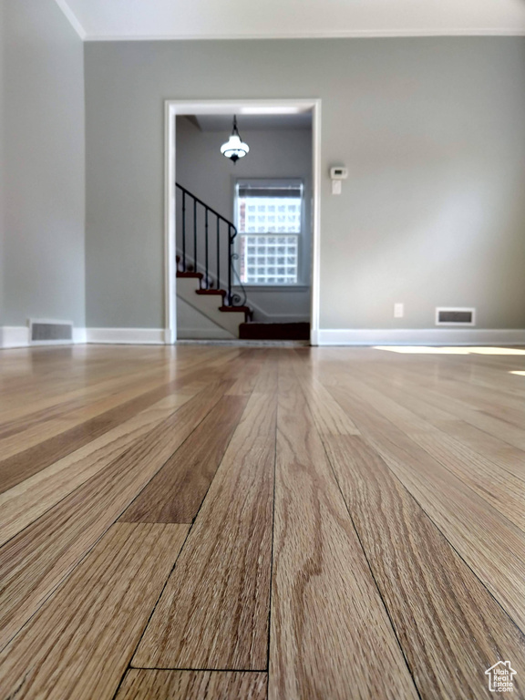 Unfurnished room with stairs, wood finished floors, a chandelier, and baseboards