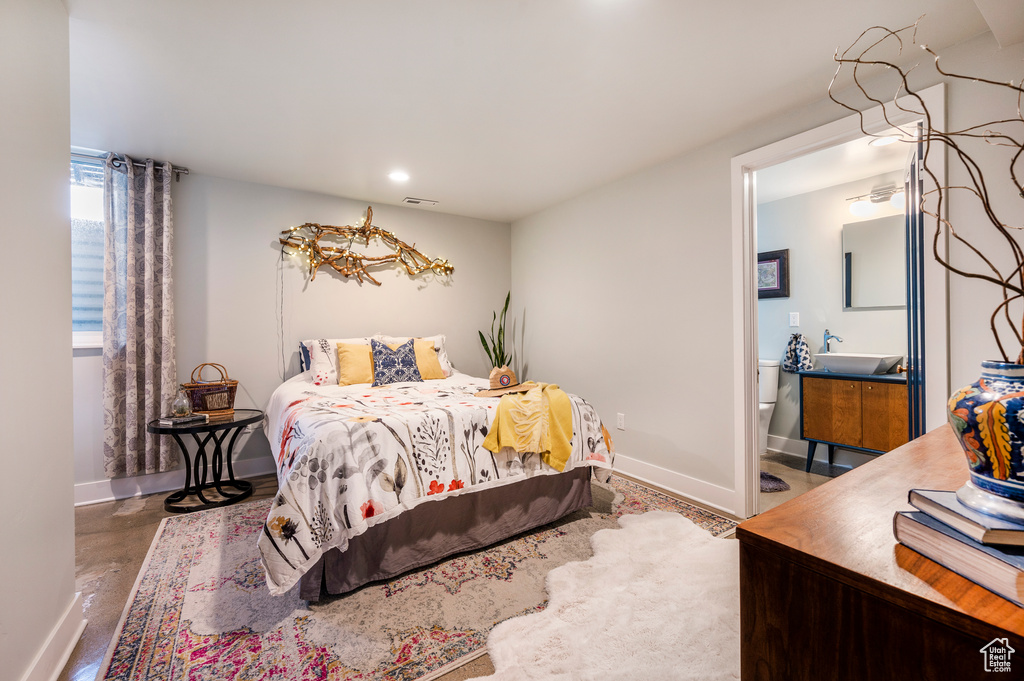 Bedroom featuring baseboards, recessed lighting, finished concrete flooring, ensuite bathroom, and a sink