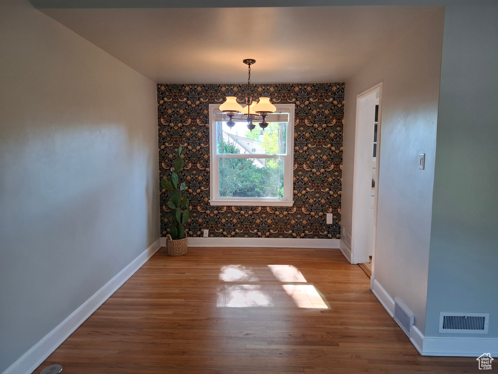Unfurnished dining area with a chandelier and wood finished floors