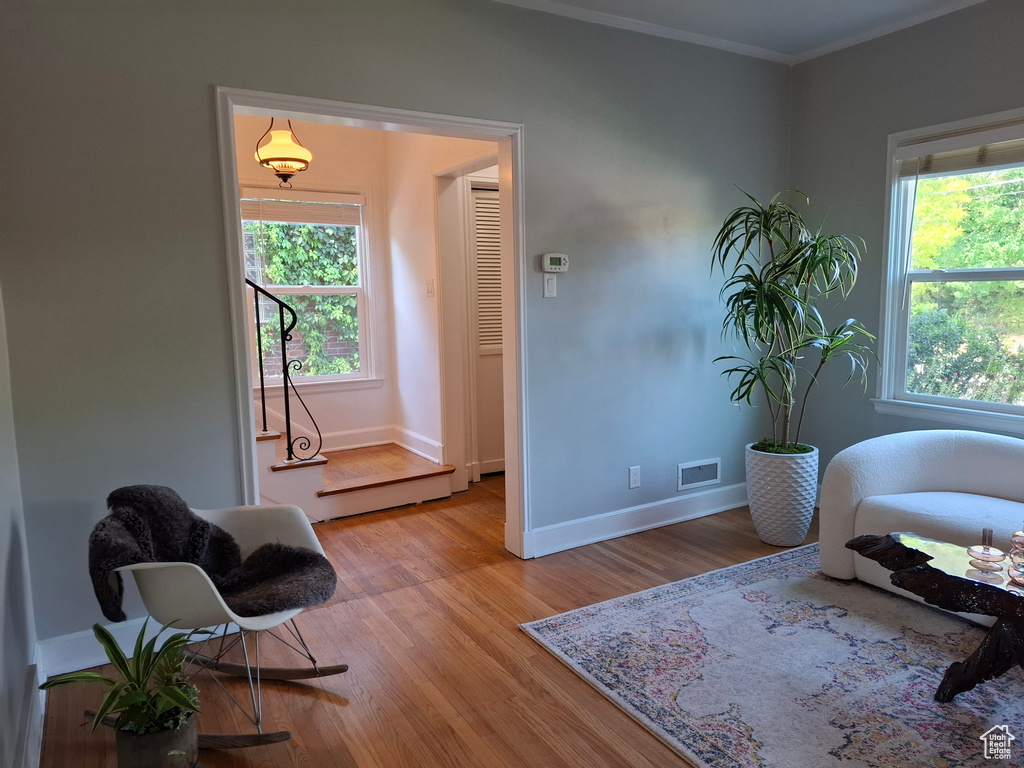 Living area with plenty of natural light, light wood-style floors, and crown molding