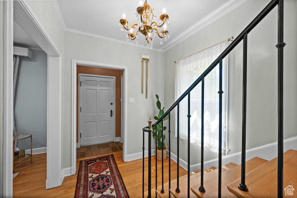 Foyer with light wood-style flooring, a chandelier, crown molding, stairway, and baseboards