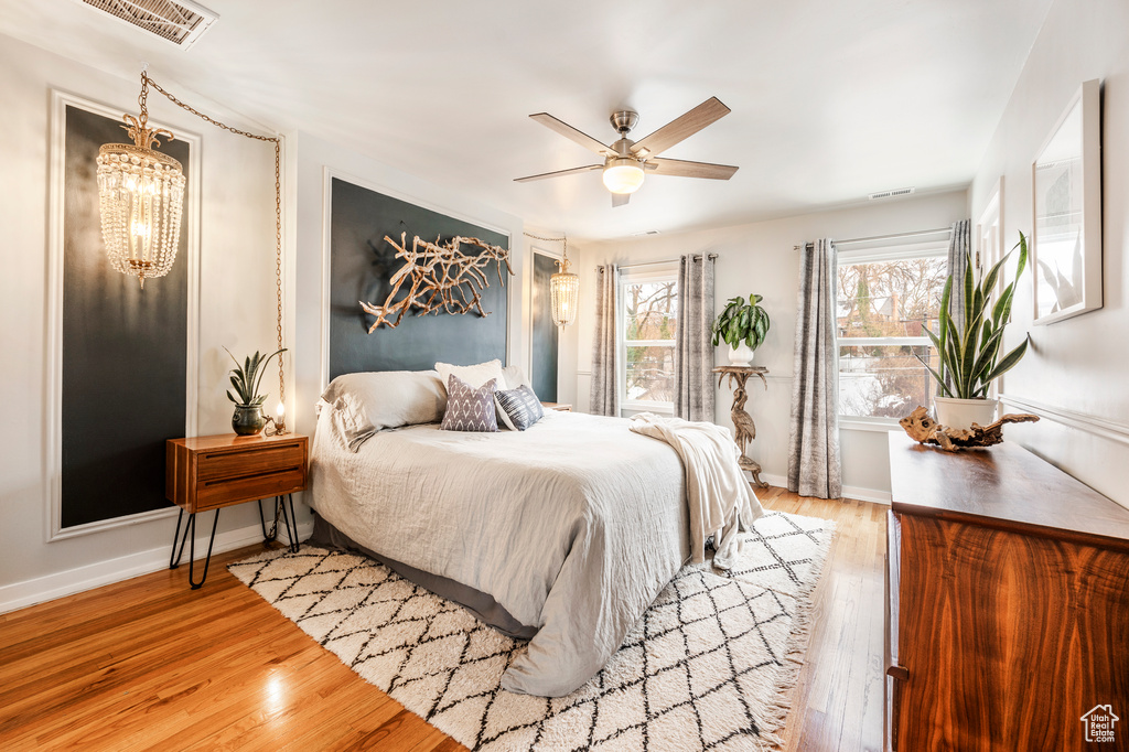 Bedroom with wood finished floors, a chandelier, baseboards, and a ceiling fan