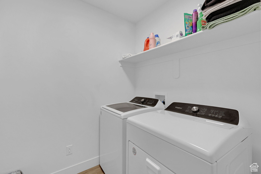 Washroom featuring independent washer and dryer, baseboards, and light wood finished floors