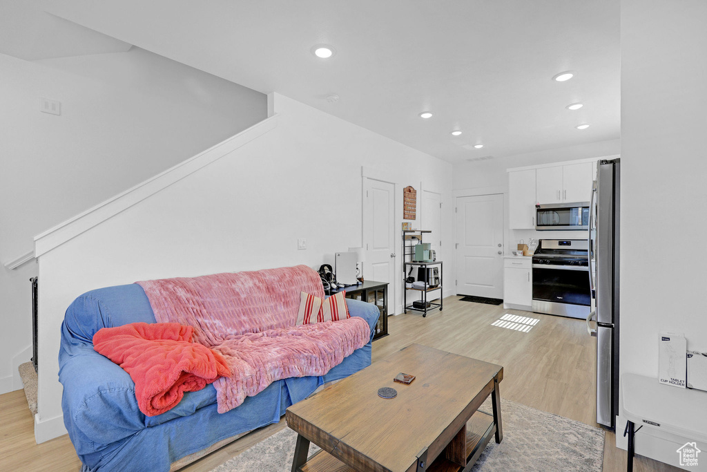 Living room with light wood finished floors and recessed lighting