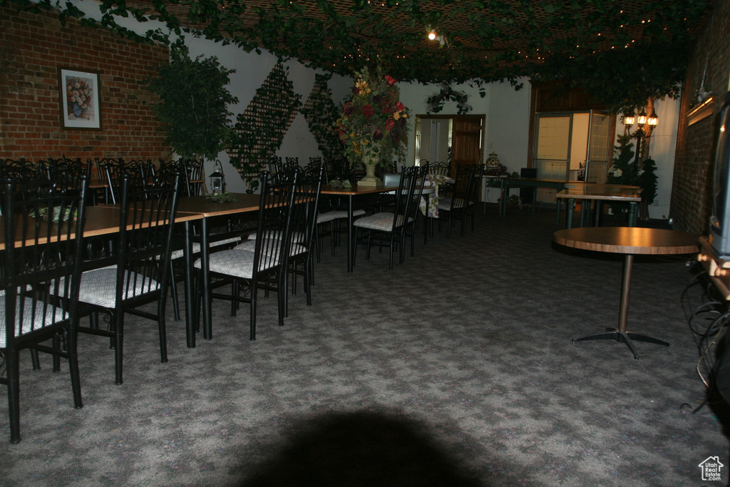 Carpeted dining area with brick wall