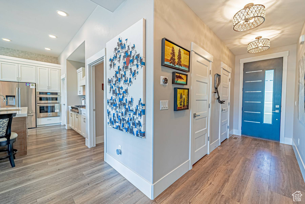 Foyer entrance with light wood finished floors, a chandelier, baseboards, and recessed lighting