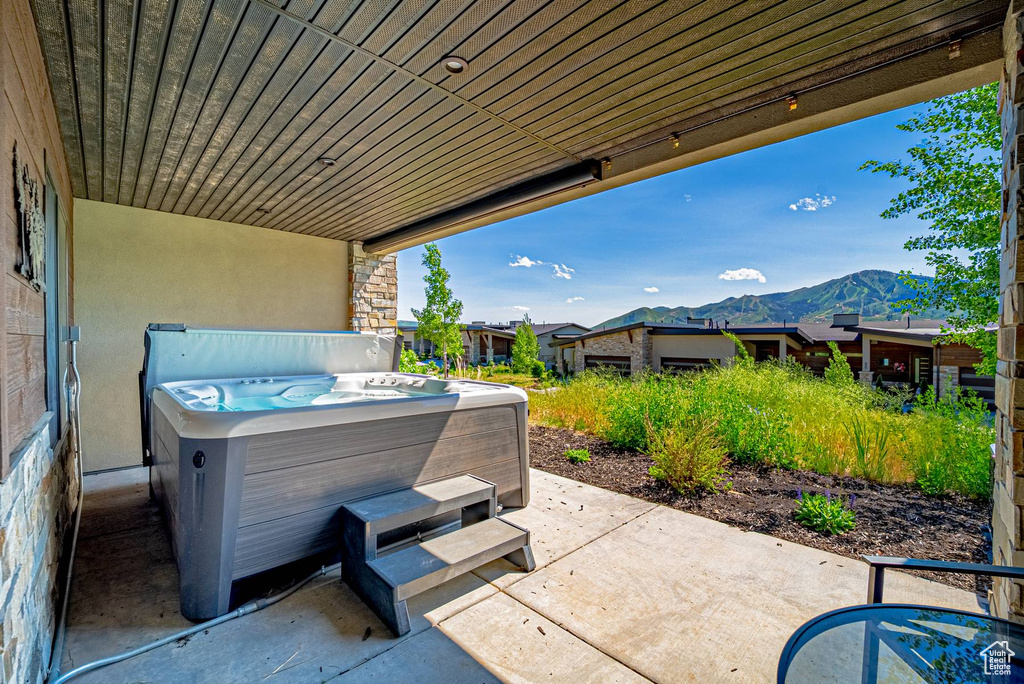 View of patio with a hot tub and a mountain view