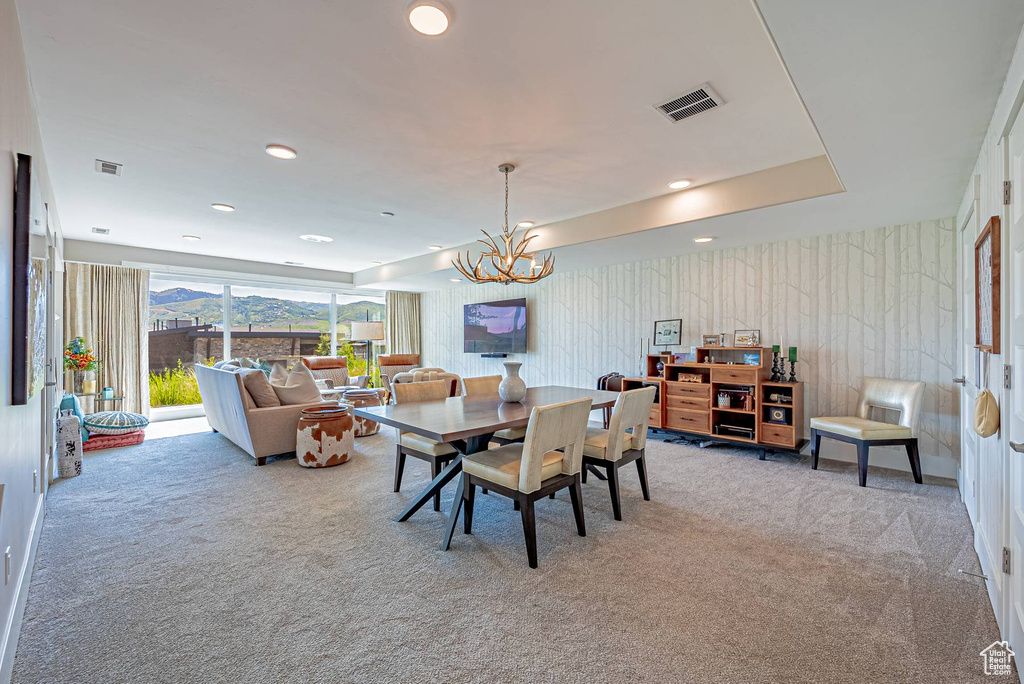 Carpeted dining space with a chandelier and recessed lighting