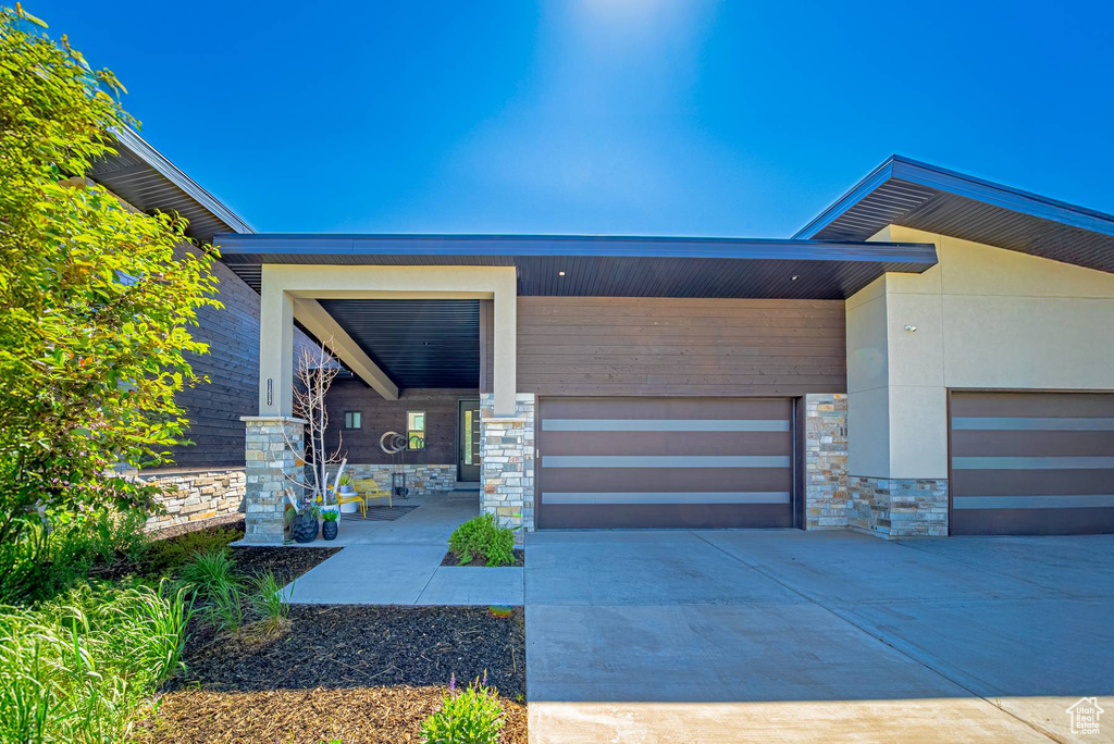 Entrance to property with stone siding, driveway, and an attached garage