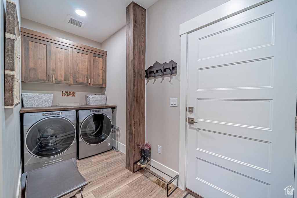 Laundry room featuring washer and clothes dryer, cabinet space, light wood finished floors, and baseboards