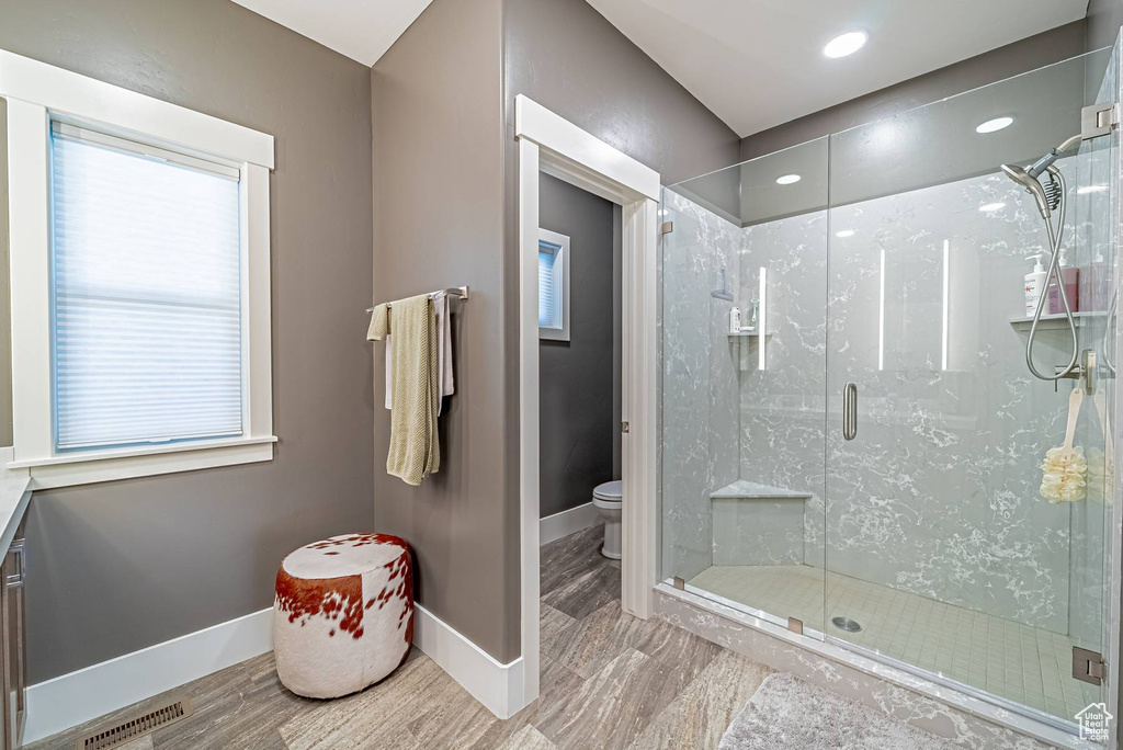 Bathroom with toilet, baseboards, a shower stall, and recessed lighting