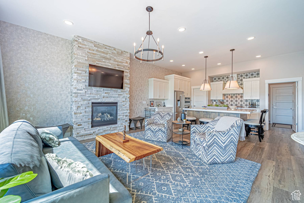 Living room with dark wood-style flooring, a chandelier, wallpapered walls, recessed lighting, and a fireplace