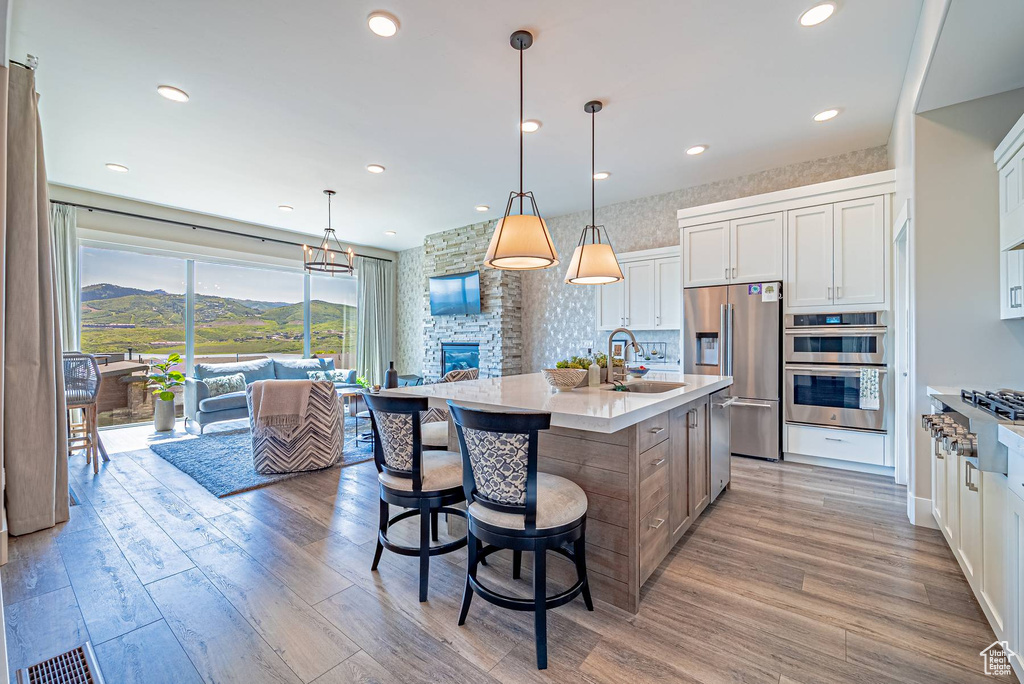 Kitchen featuring stainless steel appliances, a sink, light countertops, light wood-style flooring, and white cabinets
