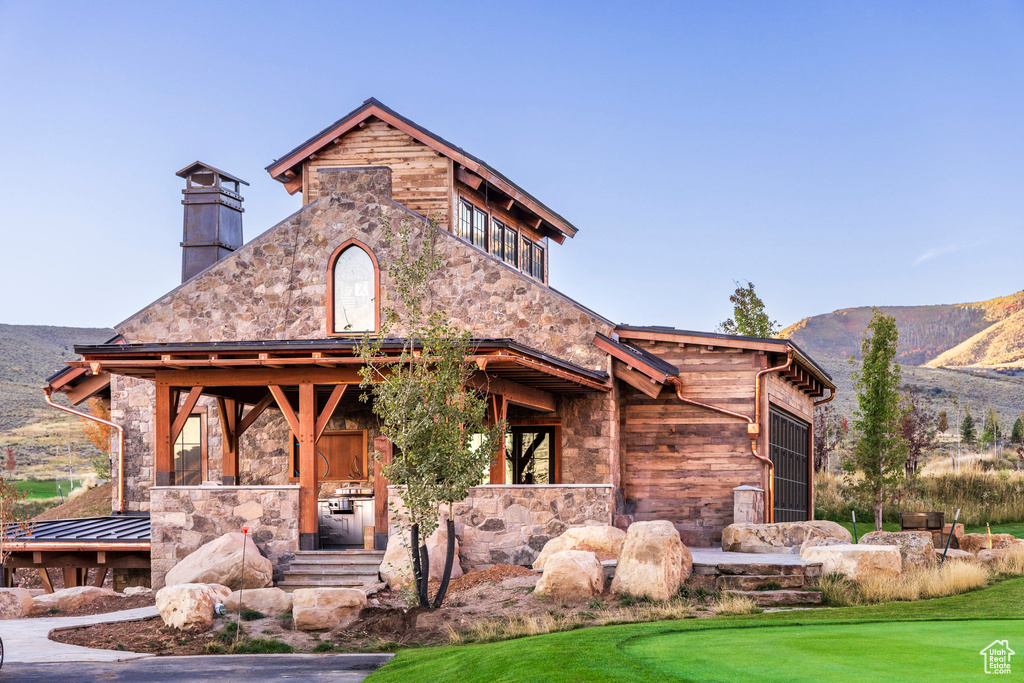 View of front of house featuring stone siding, a mountain view, and a chimney