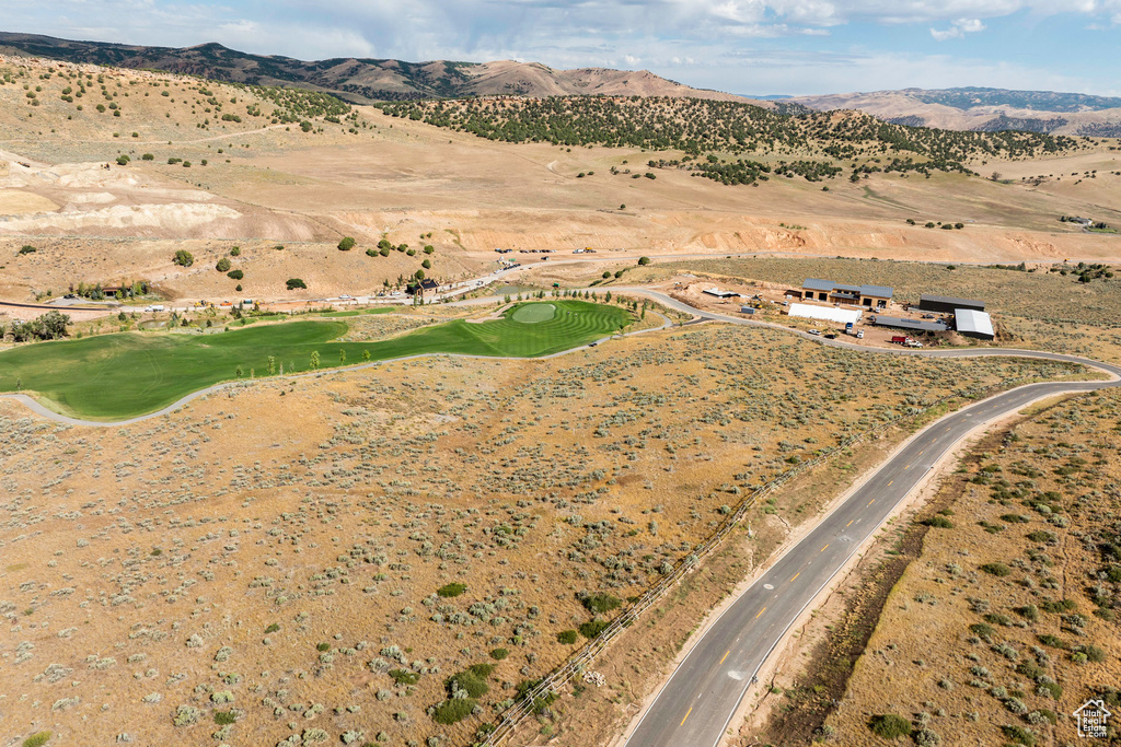 Aerial view of property and surrounding area with a mountain backdrop and a local golf course