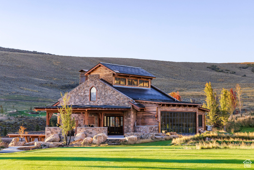 View of front facade with a front lawn, a mountain view, and stone siding