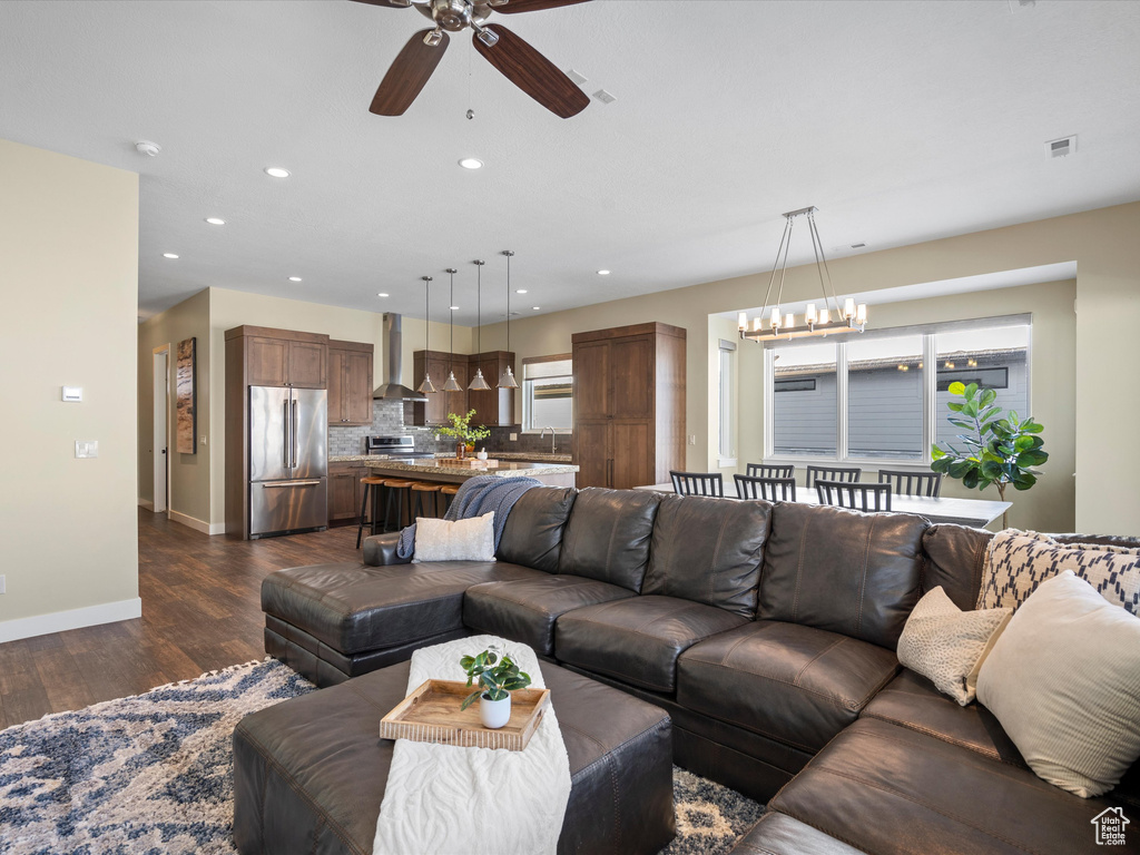 Living area with a chandelier, dark wood-style flooring, a ceiling fan, baseboards, and recessed lighting