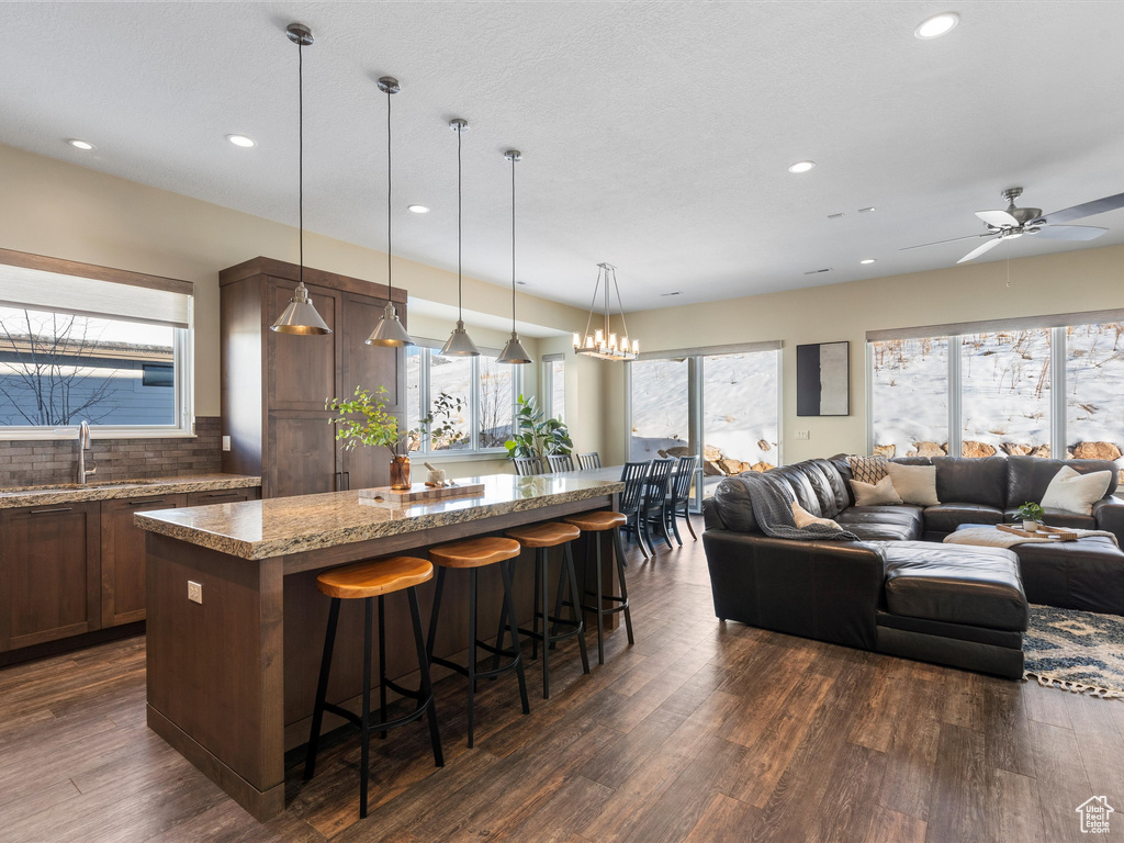Kitchen with a sink, a center island, open floor plan, dark wood-style flooring, and recessed lighting