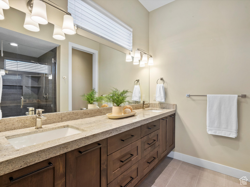 Bathroom featuring double vanity, baseboards, a stall shower, and tile patterned floors