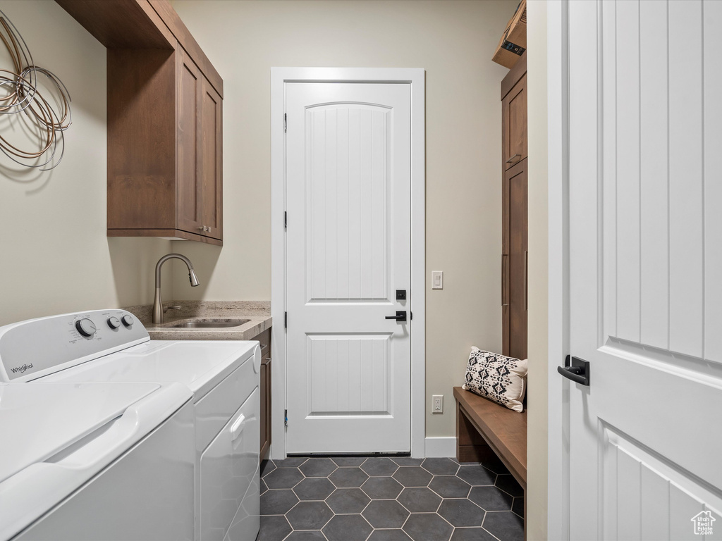 Washroom featuring cabinet space, washer and dryer, dark tile patterned flooring, and baseboards