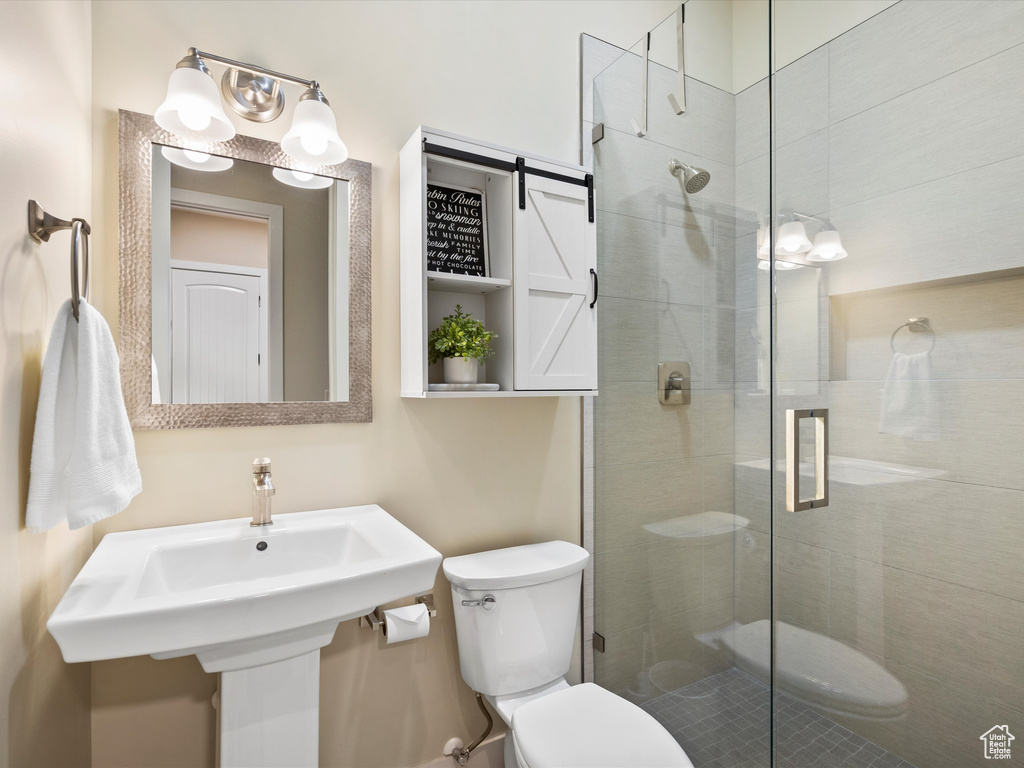 Bathroom with toilet, a stall shower, and a sink